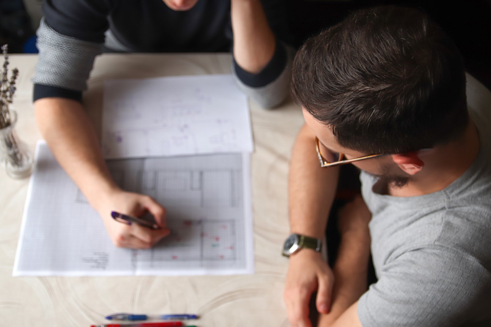 Design team collaborating at a table reviewing extensive architectural blueprints